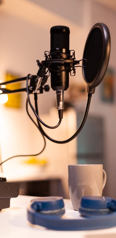Zooming on professional microphone in vlogger home studio and neon light in the background. Influencer recording social media content with production microphone. Digital web internet streaming station