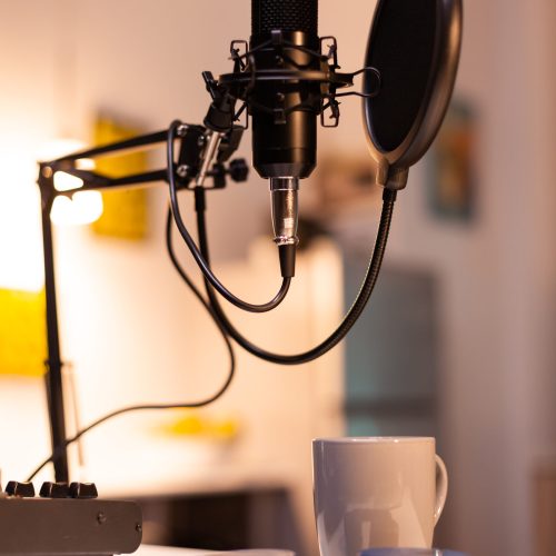 Zooming on professional microphone in vlogger home studio and neon light in the background. Influencer recording social media content with production microphone. Digital web internet streaming station